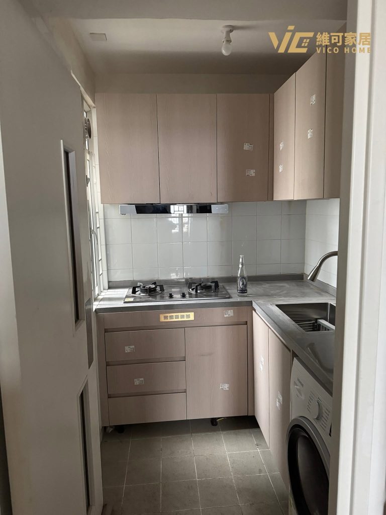 hk-custom-kitchen-service 14 淺木色無手把廚櫃配灰色石英檯面,L 型佈局,洗衣機內嵌,窗戶透入自然光。