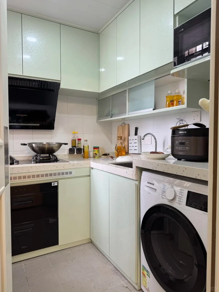 hk-custom-kitchen-service 9 淺綠色無手把廚櫃配石英檯面,L 型佈局,抽油煙機、洗衣機及微波爐內嵌。