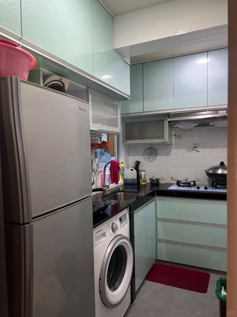 hk-custom-kitchen-service 1 淺綠色無手把廚櫃配黑色石英檯面,L 型佈局,雪櫃、洗衣機及微波爐內嵌。