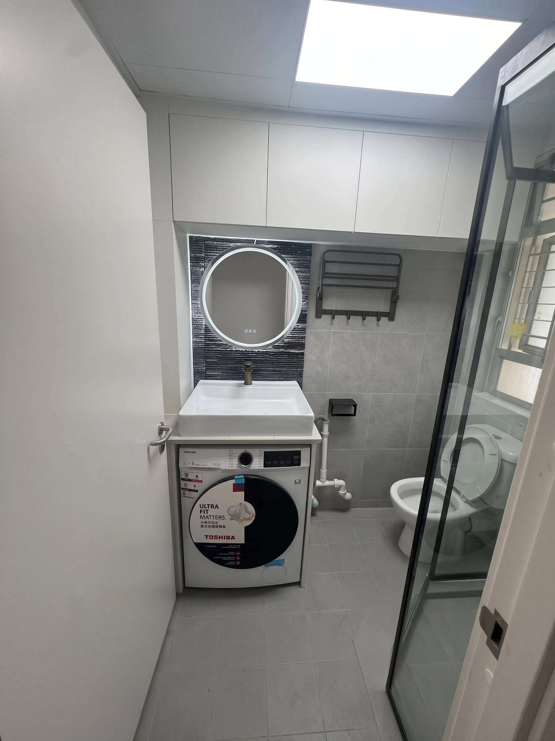 Yu Hing Court bathroom showcase: Integrated vanity and washing machine cabinet with illuminated LED mirror
